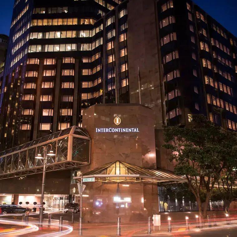 An image of the InterContinental Hotel in Wellington at night, with car headlights sweeping past the front doors with a long exposure effect. 