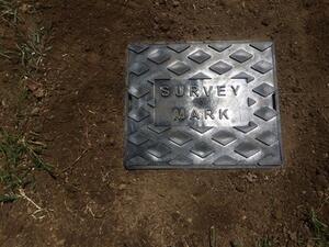 Protective black plastic box installed flushed with the ground over a geodetic mark