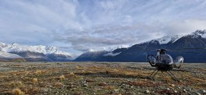 Helicopter on high country plain with mountains in background