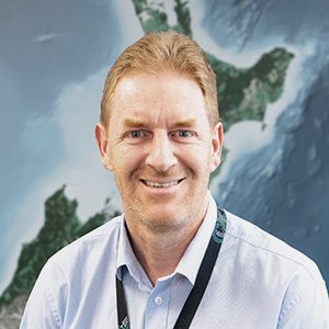 Headsot of Richard Hawke against a background map of New Zealand