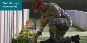 PTE Samuel Appleton places an New Zealand flag by a headstone a Buttes New British Cemetery, Belgium