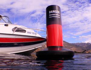 A buoy with the text "DANGER. Hessian below. Prop entanglement" next to a boat