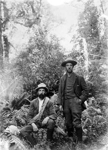 Photograph of two men surrounded by native bush. One is carrying rope.