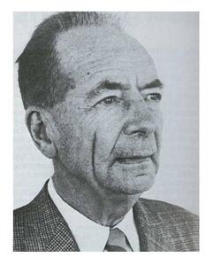 Close up of an older man's face and shoulders. He is wearing a suit and has deep smile lines.