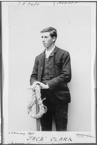 A young man posing for a photograph holding a pick and a coil of rope