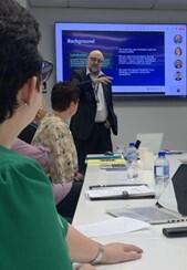 Presenter standing in front of screen, leading a discussion with a group