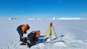 Image of the team setting up a Global Navigation Satellite System (GNSS) receiver on sea ice to calibrate the Cape Roberts tide gauge. 