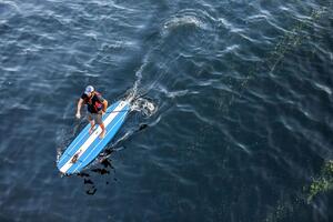 A man on a stand-up paddleboard on a lake.