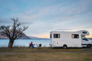 Image of a person and their campervan alongside a lake.