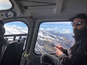 A man inside a small aircraft, mountains can be seen out the window