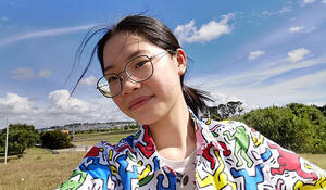 Geospatial student Kiu Hei Chloe Yip pictured with blue sky and trees in the background
