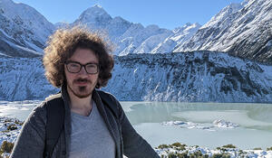 Geospatial graduate Ronny Rowe standing in front of snowy mountains