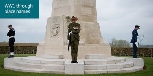 3 representatives from the navy, army and air force stand to attention but with their heads bowed in a ceremony at a monument