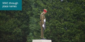 World War 1 through place names: A soldier stands at attention on a memorial plinth. The soldier's head is bowed and they hold a rifle pointed downward.