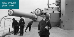 World War 1 through place names: black and white photograph with commander standing in full uniform on deck of battleship while crew are at work behind him
